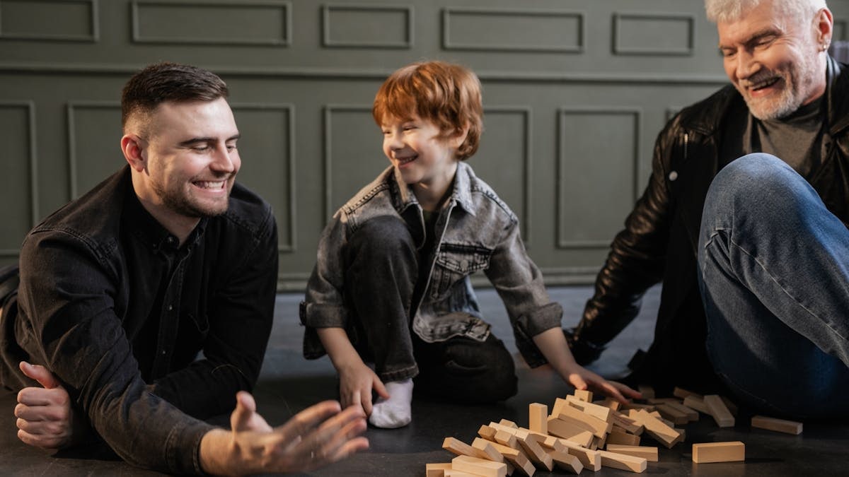 Three generations enjoying a playful Jenga game indoors, capturing happy family moments.